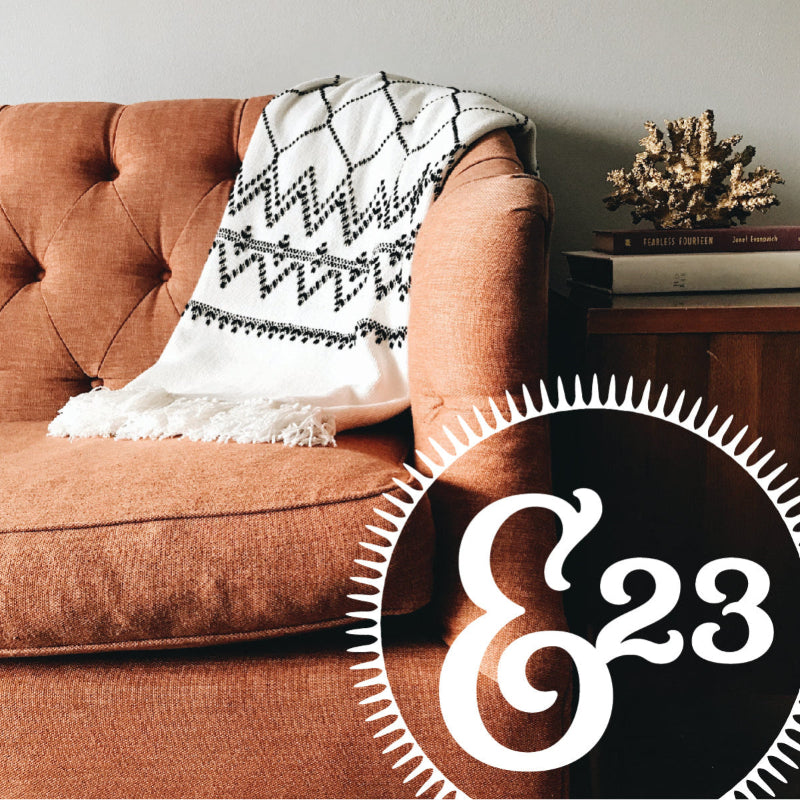 Boutique home décor scene with artisan throw blanket on vintage chair – Emporium 23 housewares and handmade accents.